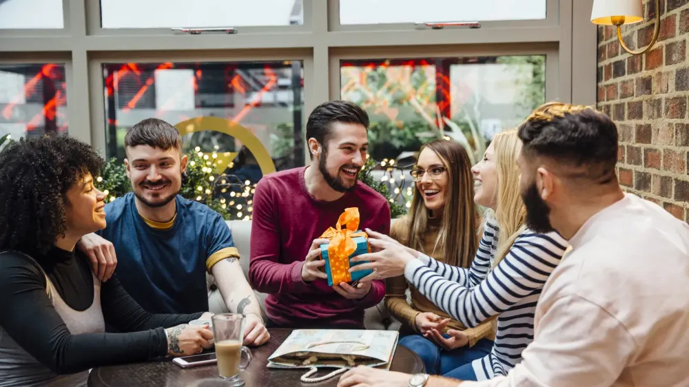 group of friends passing around a gift